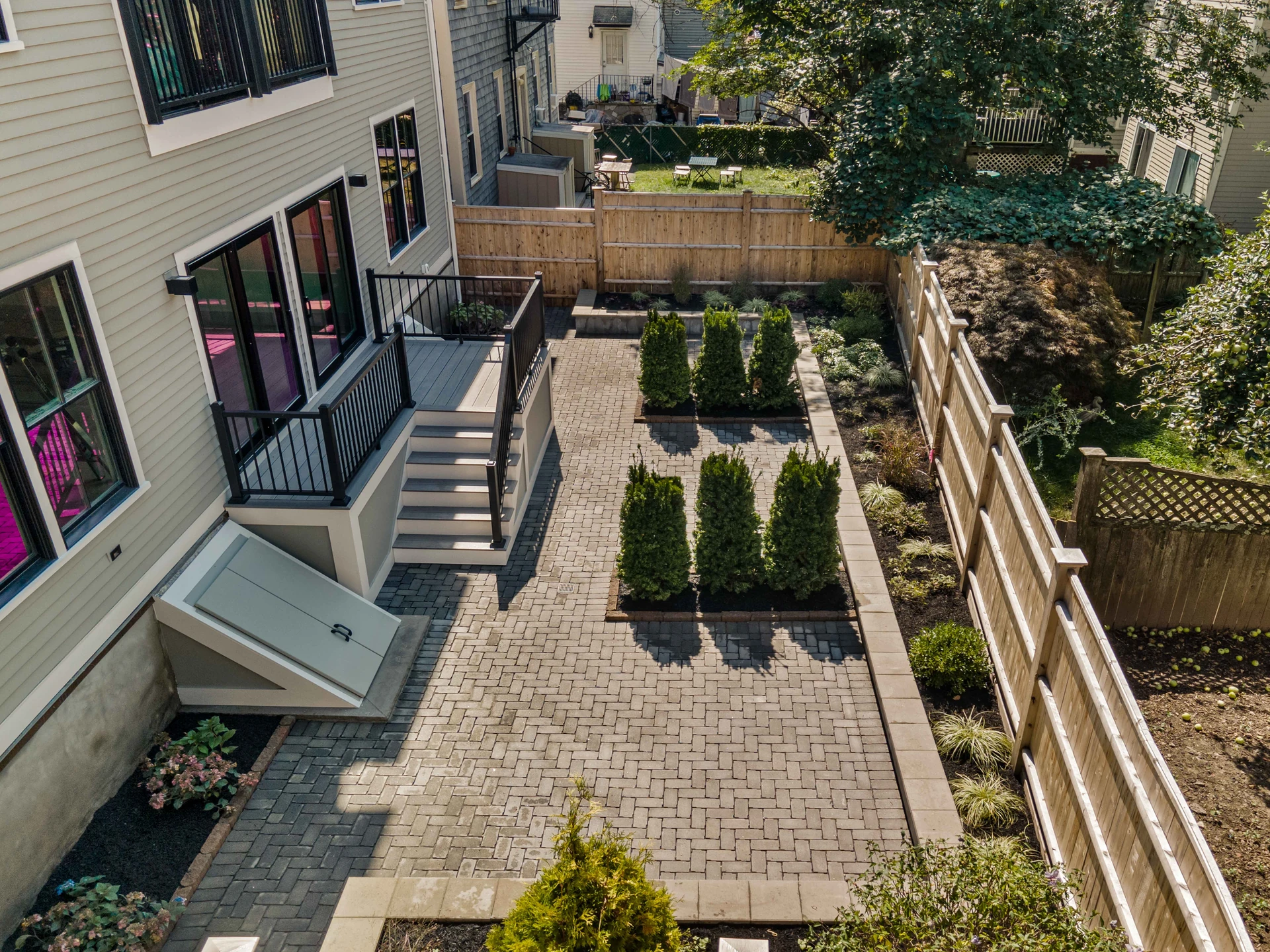 aerial-view-of-paver-patio-with-deck-and-black-deck-railing-with-big-wooden-fence