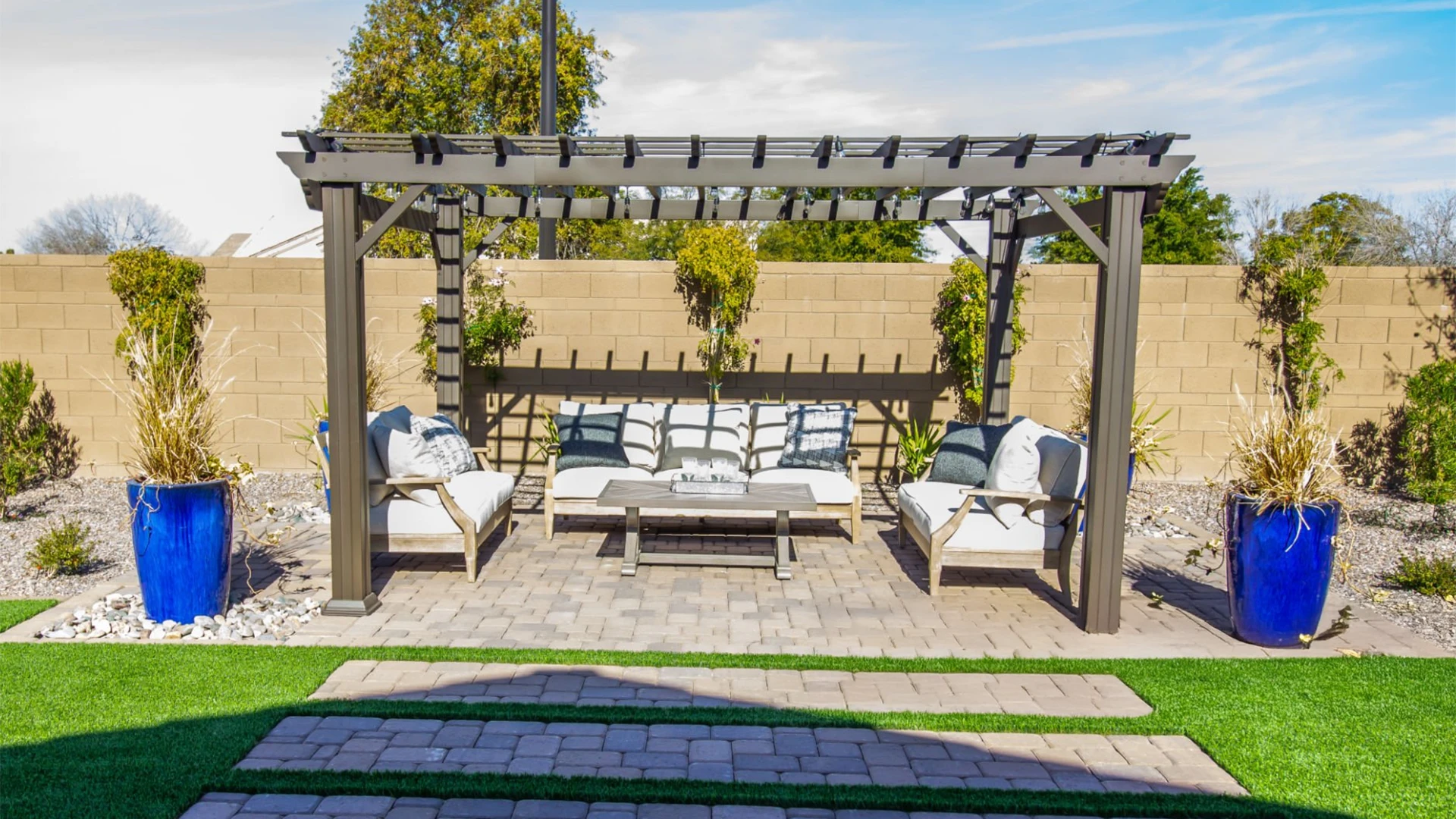 classic-wooden-pergola-covering-three-couches-and-table-with-wide-concrete-fence-on-the-back