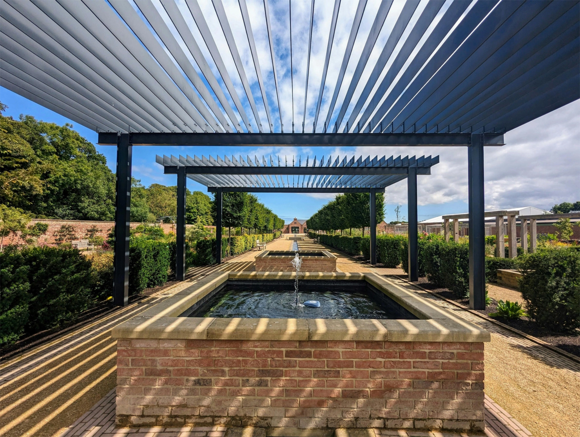 elegant-garden-louvered-pergola-with-small-fountain-featuring-nature-and-sky-scenery