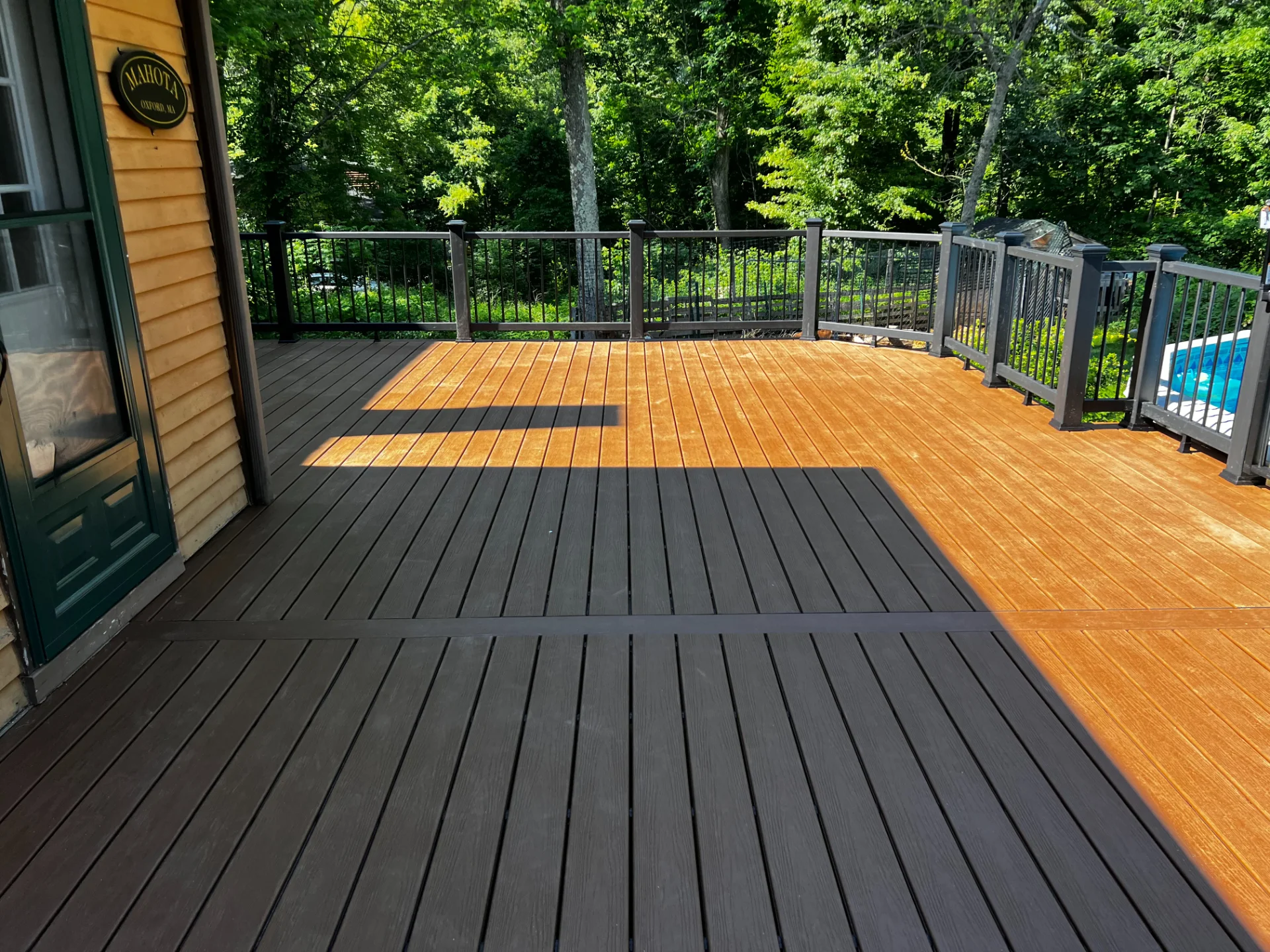 sun-kissed-wood-decking-with-black-railing-featuring-trees-view